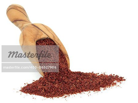 Sumac spice in an olive wood scoop over white background.