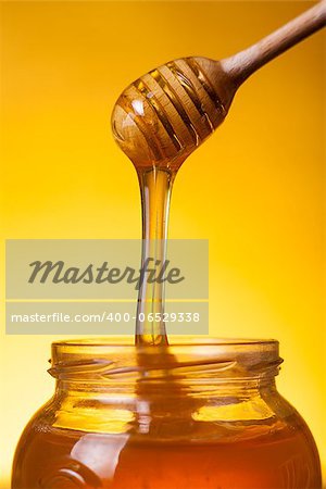 Close-up shot of flowing honey over yellow background