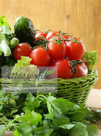 fresh vegetables (cucumbers, tomatoes, cabbage romanesco and green beans ) and herbs mix in a wicker basket