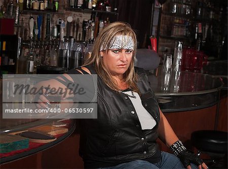Angry mature woman with alcohol leaning back in a tavern