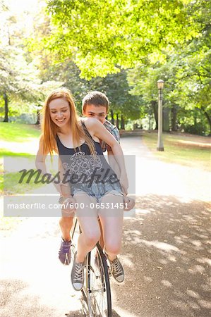 Young couple riding bike together in a park on a warm summer day in Portland, Oregon, USA