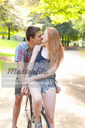 Young couple riding bike together in a park on a warm summer day in Portland, Oregon, USA