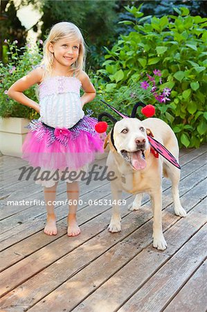 Young girl playing dress up with dog on a sunny summer afternoon in Portland, Oregon, USA