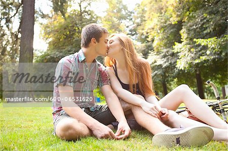 Young Couple Sitting on the Ground and Kissing in Park on a Summer Day, Portland, Oregon, USA