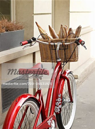 red, classic, road bicycle with wicker basket attached to handlebars filled with baguettes from bakery, Paris, France