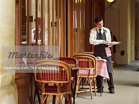waiter clearing dishes at charming outdoor cafe, Fontaine de Mars, Paris, France waiter clearing dishes at charming outdoor cafe, Fontaine de Mars, Paris, France