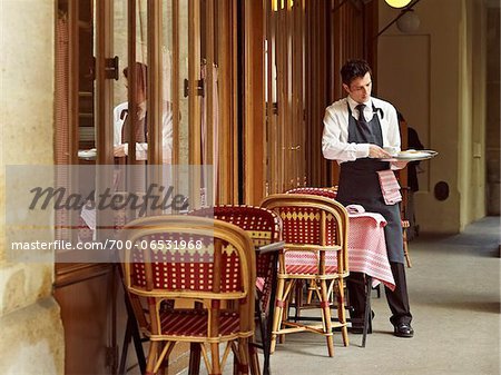 waiter clearing dishes at charming outdoor cafe, Fontaine de Mars, Paris, France