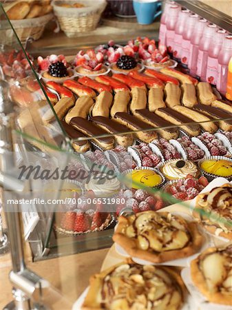 assorted sweet pastries and baked goods arranged in rows in glass bakery display case on countertop
