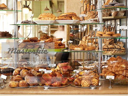 assorted pastries and baked goods stacked on display on glass shelves on bakery counter