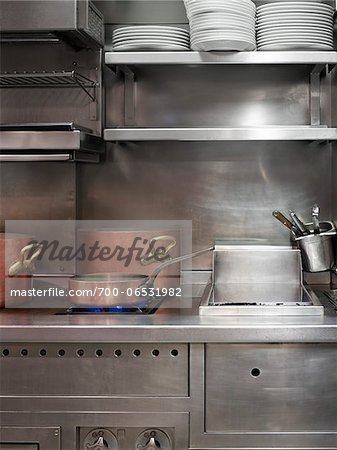 copper pots on commercial stainless steel stove in restaurant kitchen