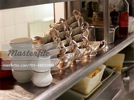 Stacks of silver gravy boats in restaurant kitchen