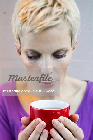 Smiling woman blowing on cup of tea