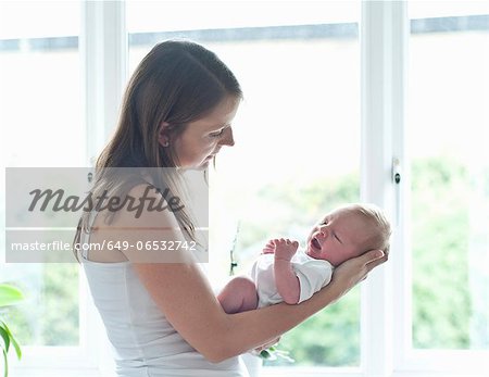 Mother holding infant son by window