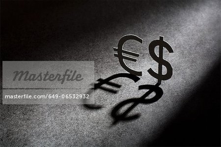 Metal currency signs casting shadow