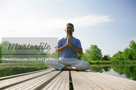 Man meditating on wooden pier