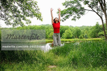 Woman jumping by rural lake