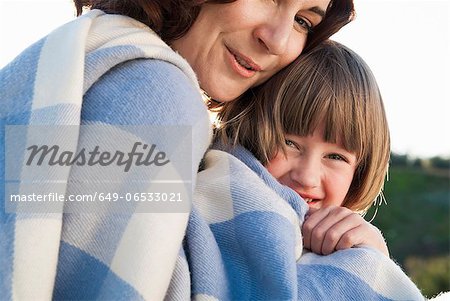 Mother and daughter wrapped in blanket