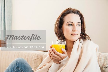 Woman having cup of juice on sofa