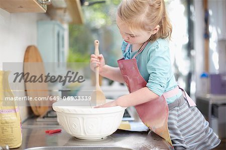 Girl mixing dough in kitchen
