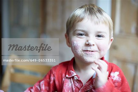 Boys face covered in flour in kitchen