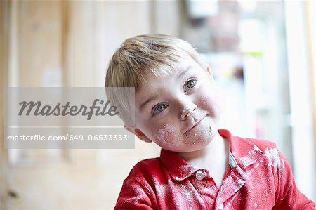 Boys face covered in flour in kitchen