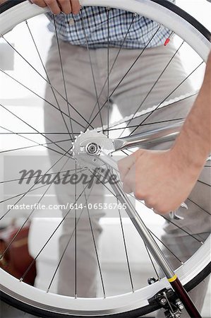 Man fixing bicycle wheel indoors