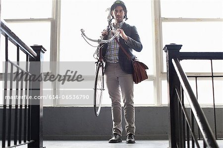 Man carrying bicycle on staircase