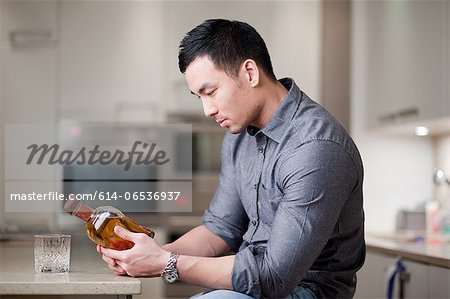 Man examining whiskey bottle in kitchen