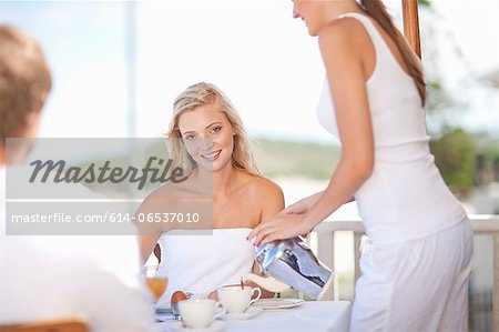 Waitress serving woman coffee at table