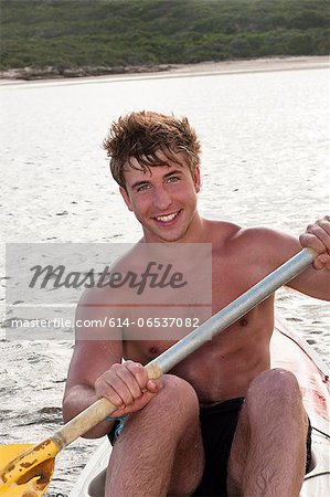 Smiling man rowing kayak in lake