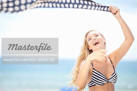 Woman playing with scarf on beach