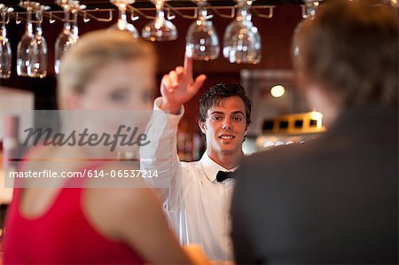 Waiter offering more drinks at bar