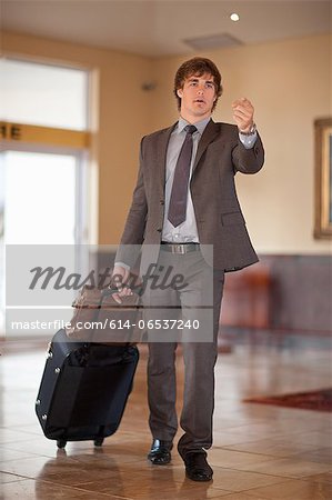 Businessman rolling luggage in lobby Businessman rolling luggage in lobby