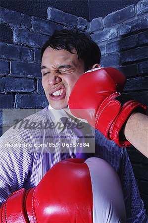 Businessman with boxing gloves getting punched