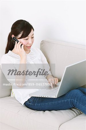 Woman using laptop and phone on the sofa