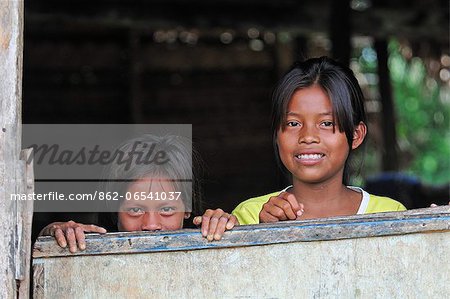 Two young girls looking out of a window, Amacayon Indian Village, Amazon river, Puerto Narino, Colombia