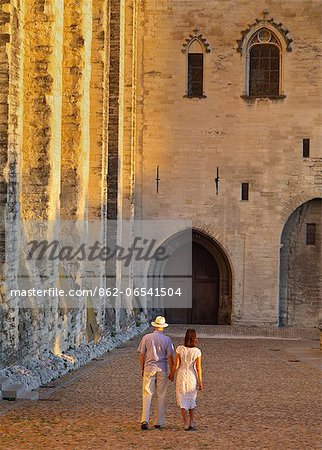 France, Provence, Avignon, Palais de Papes, Man and woman walking down cobbled road MR