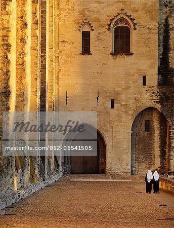 France, Provence, Avignon, Palais de Papes, Two nuns walking down cobbled road