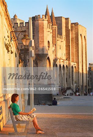 France, Provence, Avignon, Palais de Papes, Woman reading book on bench MR