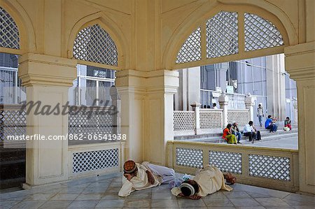 India, Andhra Pradesh, Hyderabad. Pilgrims rest near the main entrance to the prayer halls of the 16th century Mecca Masjid mosque in the Old City of Hyderabad.