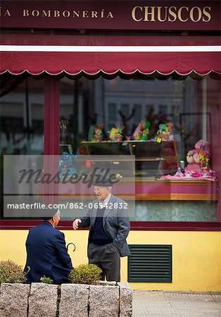 Spain, Galicia, Camino Frances, Two elderly Galician men talking in front of a shop