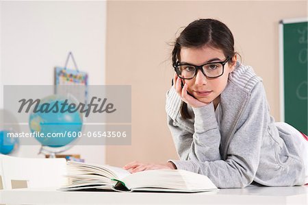 Girl Lying on Stomach Reading Book in Classroom, Mannheim, Baden-Wurttemberg, Germany
