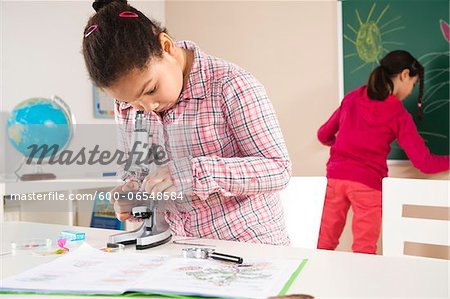 Girl Looking at Flower with Microscope in Classroom, Baden-Wurttemberg, Germany