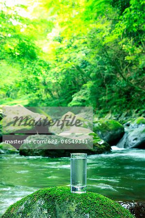 Glass of water near a mountain stream