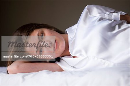 Portrait of woman lying on her bed in her bedroom.