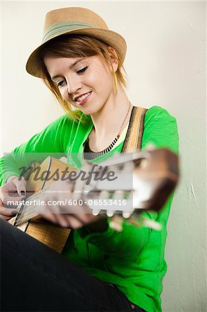 Portrait of Teenage Girl Wearing Hat and Playing Acoustic Guitar, Studio Shot on White Background