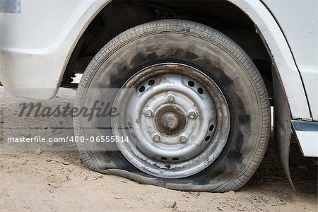 Deflated damaged tyre on white car wheel