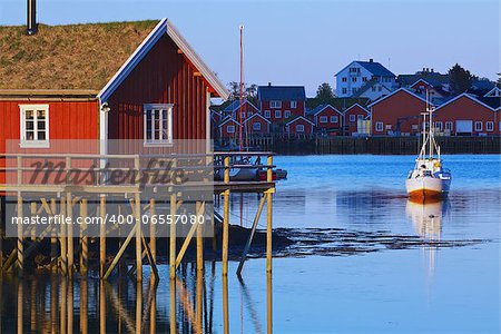 Typical red rorbu hut with sod roof lit by midnight sun in town of Reine on Lofoten islands in Norway