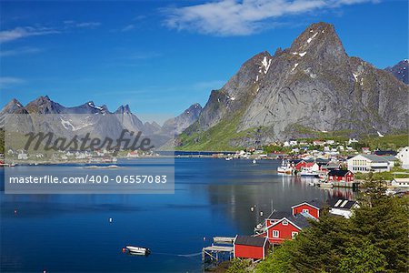 Scenic town of Reine, Norway on sunny summer day with picturesque fjord and surrounding mountain peaks