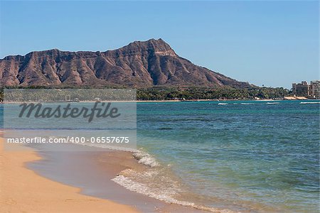A view of Diamond Head over the blue waters of Waikiki beach.
